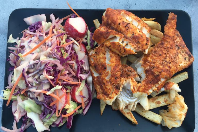 Image of cajun spiced cod on fries with side coleslaw.